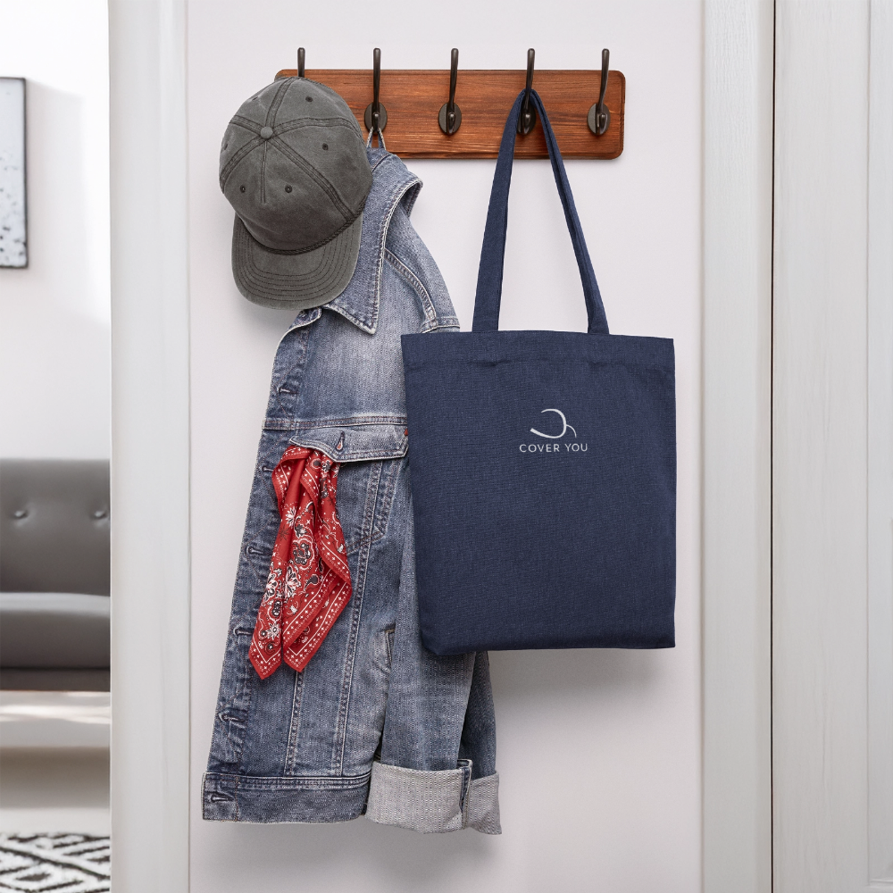 Tote bag COVER YOU bleu chiné suspendu à une patère près d'une veste en jean